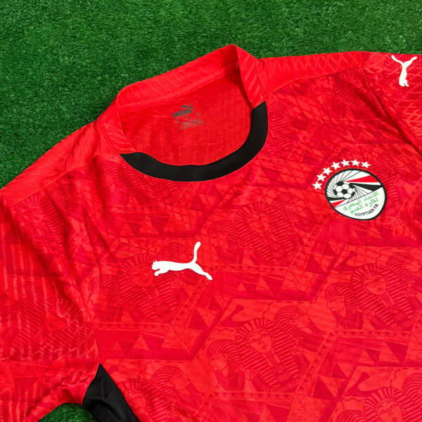 Maillot domicile Égypte 2025, rouge classique avec détails noirs.