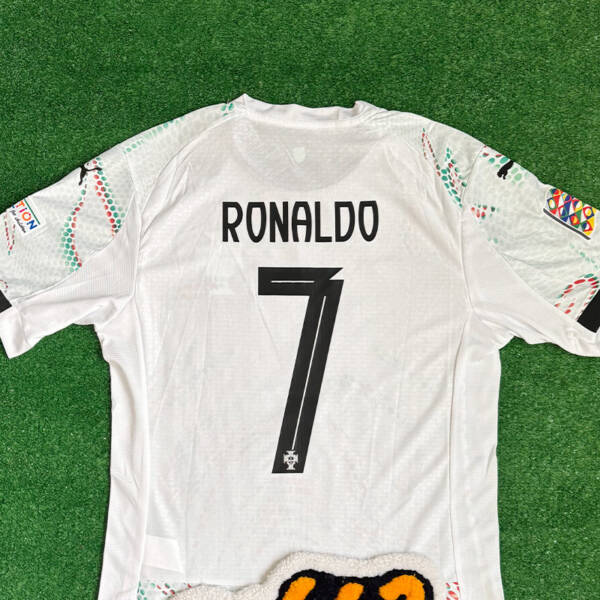 Maillot extérieur Portugal 2025 blanc, motifs vert et rouge.